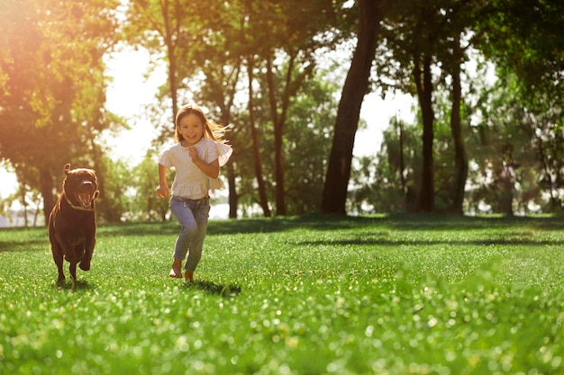 Small girl and labrodor running in the park full length shot