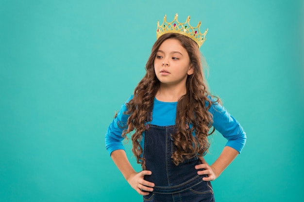 Small girl in queen crown. feel herself like big boss. being an egoist. reward for real champion. little princess. selfish kid long curly hair. luxury and success. find your motivation. copy space.