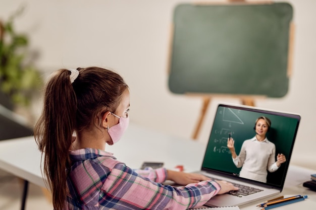 Small girl using laptop and following online class due to COVID19 pandemic