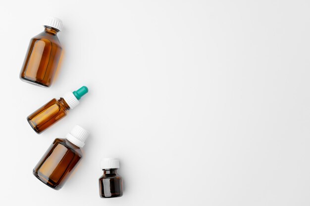 Small glass bottles with medication on white background flat lay