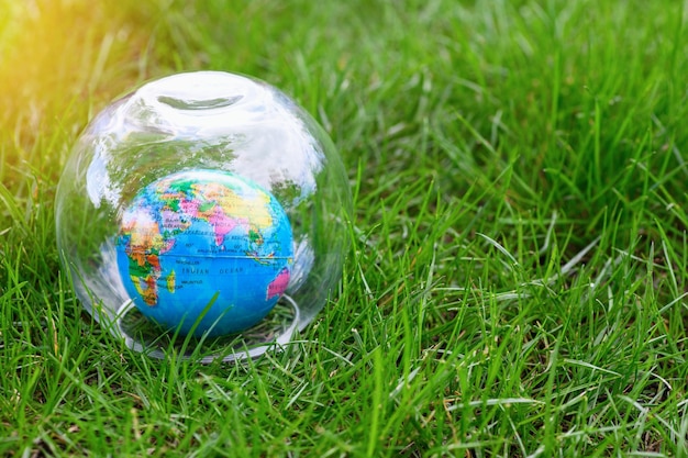 Small globe under a glass cover depicting Africa India and others on green grass in summer World hunger and crisis concept