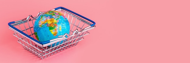 Small globe in a Shopping cart on a pink background