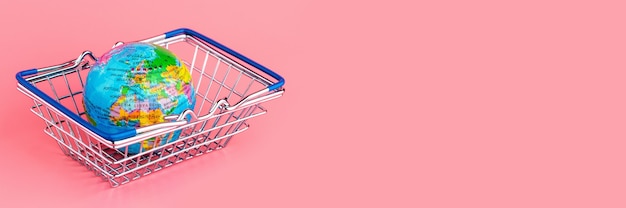 Small globe in a shopping cart on a pink background