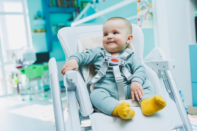 A small handsome boy is sitting in a high chair for feeding Children's kitchen chair for eating Children's furniture