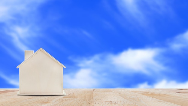 Small home model on wooden table with blue sky backgroundFamily life and Business real