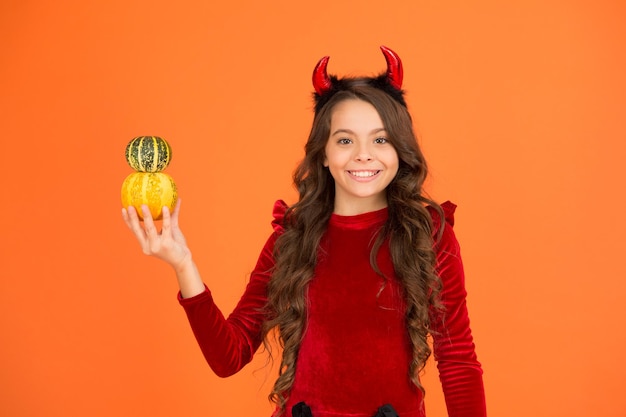 Small imp girl play with pumpkins Happy holidays Cute child celebrate Halloween Having fun Autumn holidays Pumpkins traditional attribute of fall holidays Decorations for holidays Grocery shop