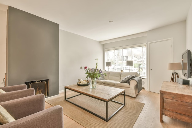 A small living room with a fireplace next to a sofa a carpet on the floor and a vase with plants