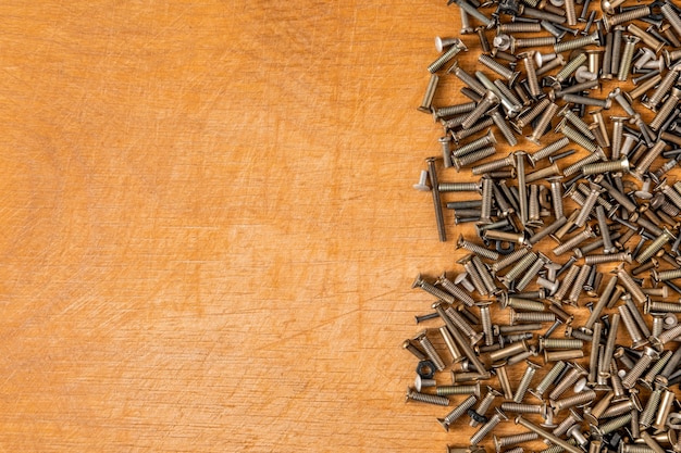 Small metal bolts and screws of different sizes and colors are scattered on a wooden table to the right.