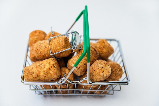 A small metal shopping cart in a supermarket on a white backgroundThere are wine and champagne corks in the basketPurchase of alcoholic beverages