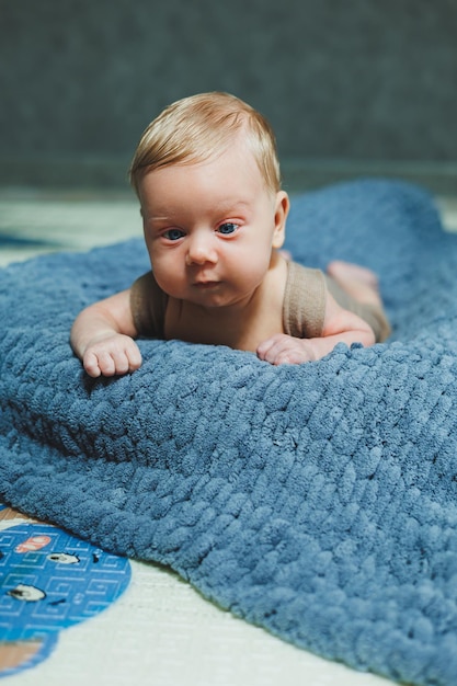 A small newborn boy lies on a gray knitted blanket Portrait of a onemonthold baby