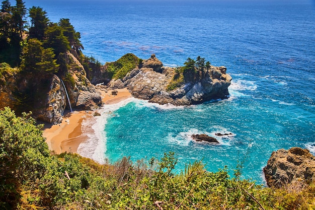 Small ocean cove surrounded by cliffs waterfall and sandy beaches