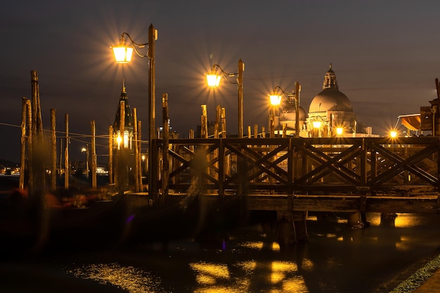 Small pier in Venice at night  and the Basilica of Santa Maria della Salud in the background