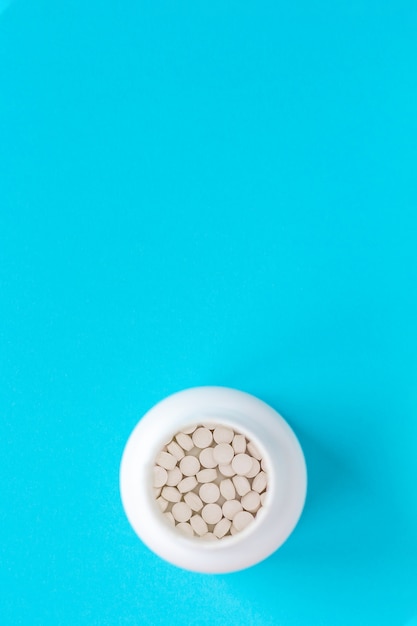 Small pills in plastic jar. Top view background