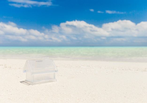 A small plastic house on a beach with a blue sky in the background.