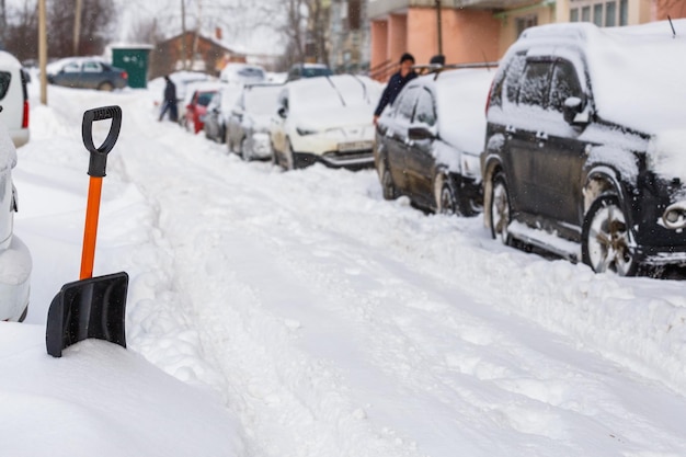 Small plastic snow shovel near snowcovered cars at sunny winter morning