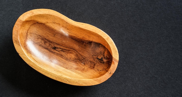 Small polished rosewood bowl on black table, closeup view from above