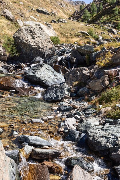 Small pond of clear water with pebbles and cobblestones between rapids of mountain gorge