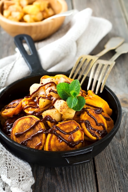 Small pumpkin pancakes with chocolate sauce in pan on the old vintage