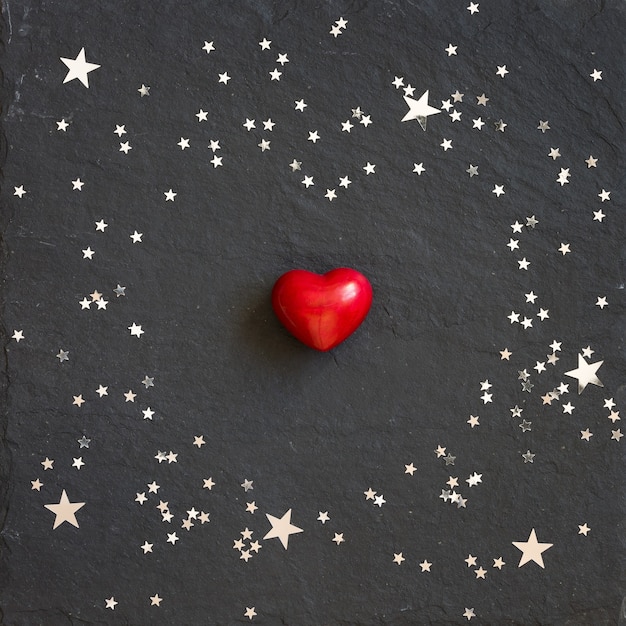 Photo small red heart on the black background with silver stars