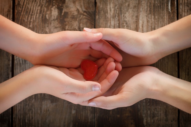 Small red heart lies in the hands of men and women, the concept of love and romance.