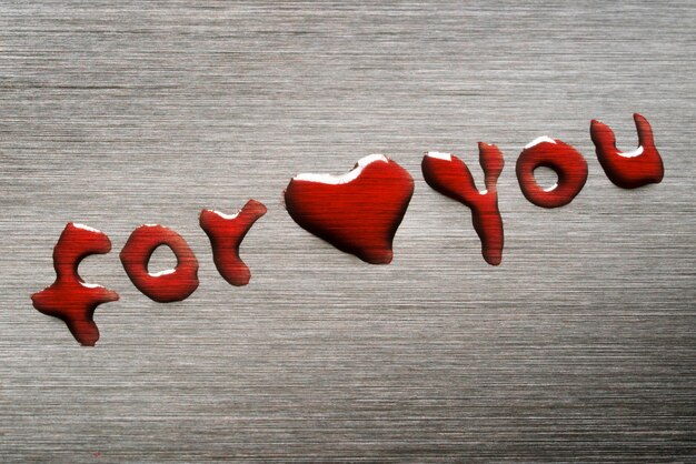 A small red heart on a metal surface with the inscription for you