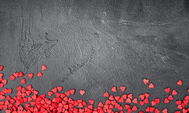 Photo small red hearts on a dark concrete background, valentine's day background