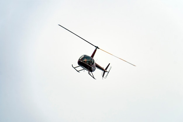 A small red helicopter flying in the sky