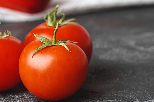 Small red ripe cherry tomatoes with leaves on table