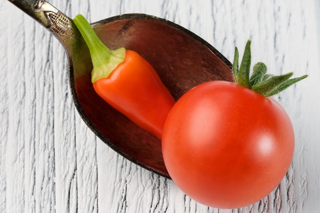 Small red ripe tomato with red hot pepper