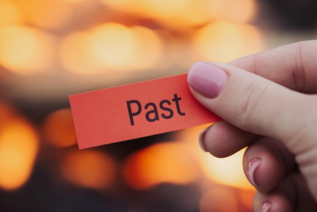 Small red sheet of paper in female hand with word past on it Release from pain mistakes and problems of the past