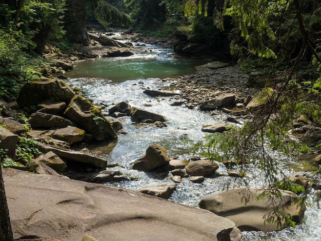 Small river flowing rapidly and vividly through its wild stony valley