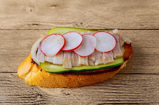 Small sandwiches with vegetables fish cucumber onion radish sandwich herring wooden background top v