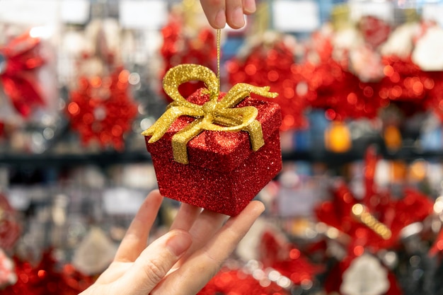 Small shiny red gift box with golden ribbon in women hands. Present for special date, birthday, anniversary or wedding. Boxing Day or Valentine Day as symbol of love and affection.