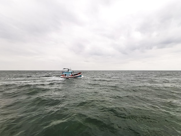 Small ship is sailing on the sea around with white cloud background