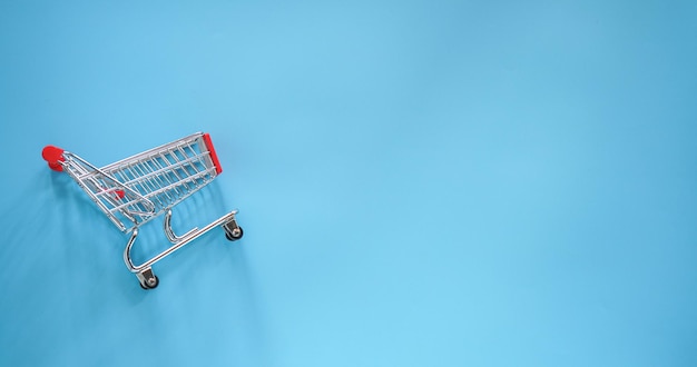 Small shoppingcart on blue background with copy space