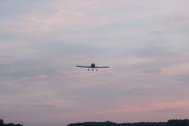 Small single engine airplane flying against sunset sky