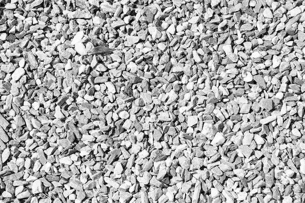 Small stones or gravels natural texture outdoors on sunny day on grey pebble background