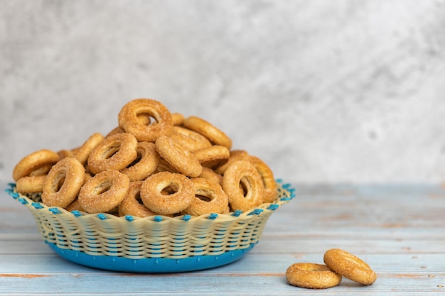 Small sweet bagels in a wicker bowl on light blue wooden background