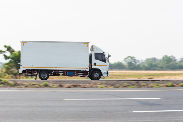 Small truck driving on the highway Small white delivery truck moving fast on road distribution business express delivery service