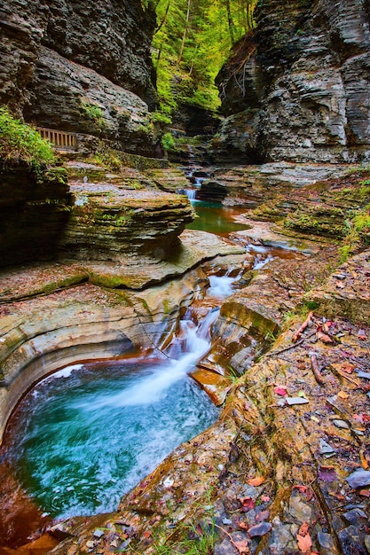 Small waterfalls along stunning blue river in gorge of New York with fall foliage and terraced rocks