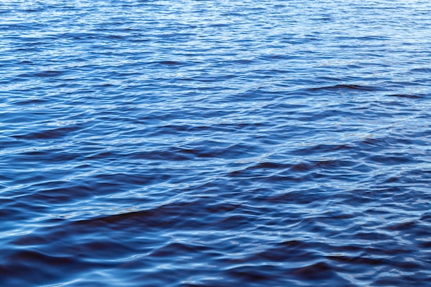 Small waves on the surface of the lake. Beautiful texture of blue water. On a sunny day