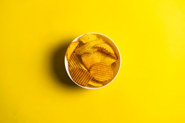 A small white bowl with yellow crisp potato chips