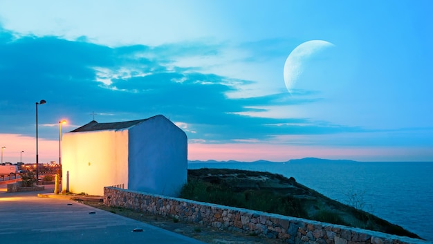 Small white church at dusk under a huge moon