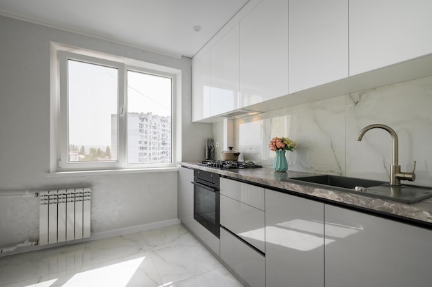 Small white modern domestic kitchen interior with furniture