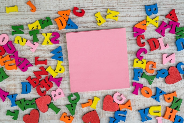 Small wooden random colorful letters with empty memo on table for education ABC