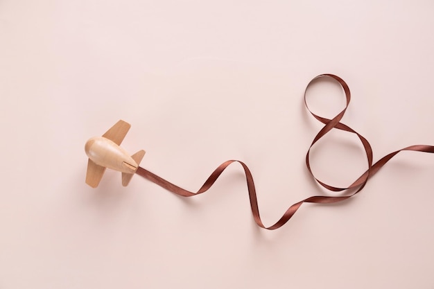 Small wooden toy airplane carries a figure-shaped ribbon 8