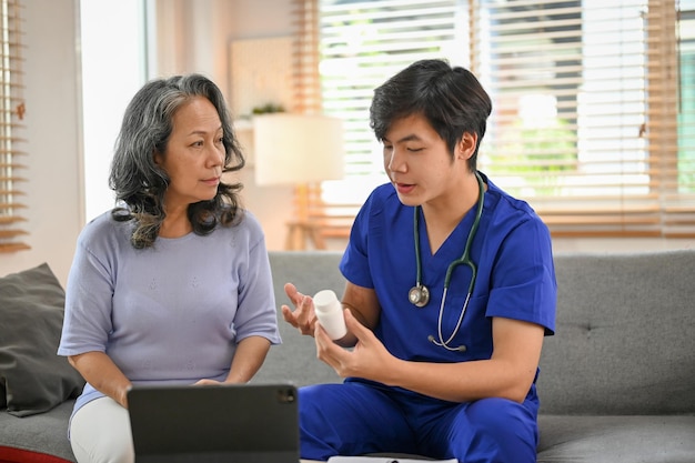 Smart Asian male doctor gives an instruction and explains the use of medicine to an old lady