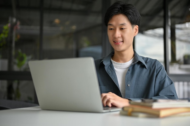 Smart Asian male office worker remote working at the coffee shop using laptop