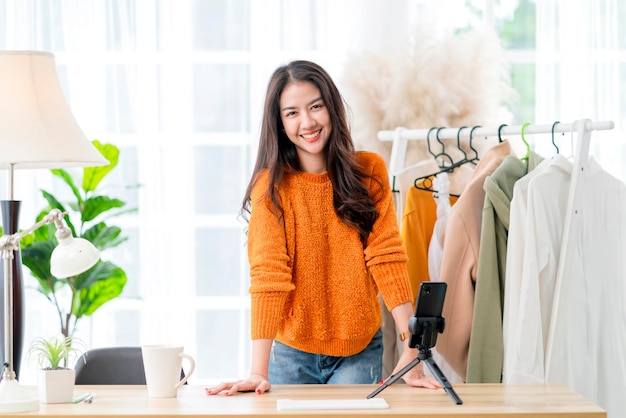 Smart attractive smiling asian female business owner entrepreneur hand hold coffee cup portrait shot looking at camera with confidentwoman sitting on table at home studio