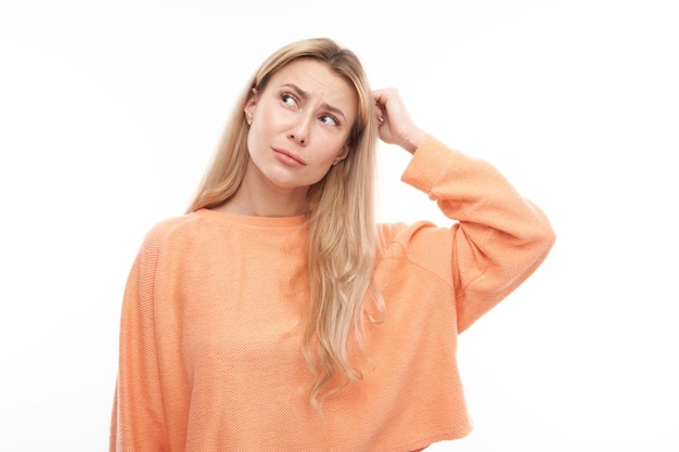 Smart blonde girl in casual holding her head thinks doubts makes decision isolated on white studio background